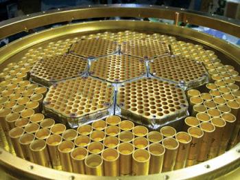 This honeycomb-like array of feedhorns at the 10-m South Pole Telescope directs radiation to superconducting detectors used to measure the polarization of the cosmic microwave background. The seven hexagonal cells in the center, about 5.8 cm across, are sensitive to radiation at frequencies of about 150 GHz. The larger feedhorns surrounding them are used for frequencies near 95 GHz. Progress in detector development is so rapid that within a year arrays should have sensitivities an order of magnitude greater than that of the state-of-the-art detector shown here. (Courtesy of the South Pole Telescope.)