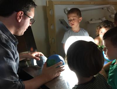 Jason Henning (left), a post-doctoral fellow at the Kavli Institute for Cosmological Physics at the University of Chicago, talks about eclipses with children Tuesday at the Bright Horizons at Lakeview, a Chicago pre-school on Lincoln Avenue. <i>Credit:</i> Neil Steinberg/Sun-Times